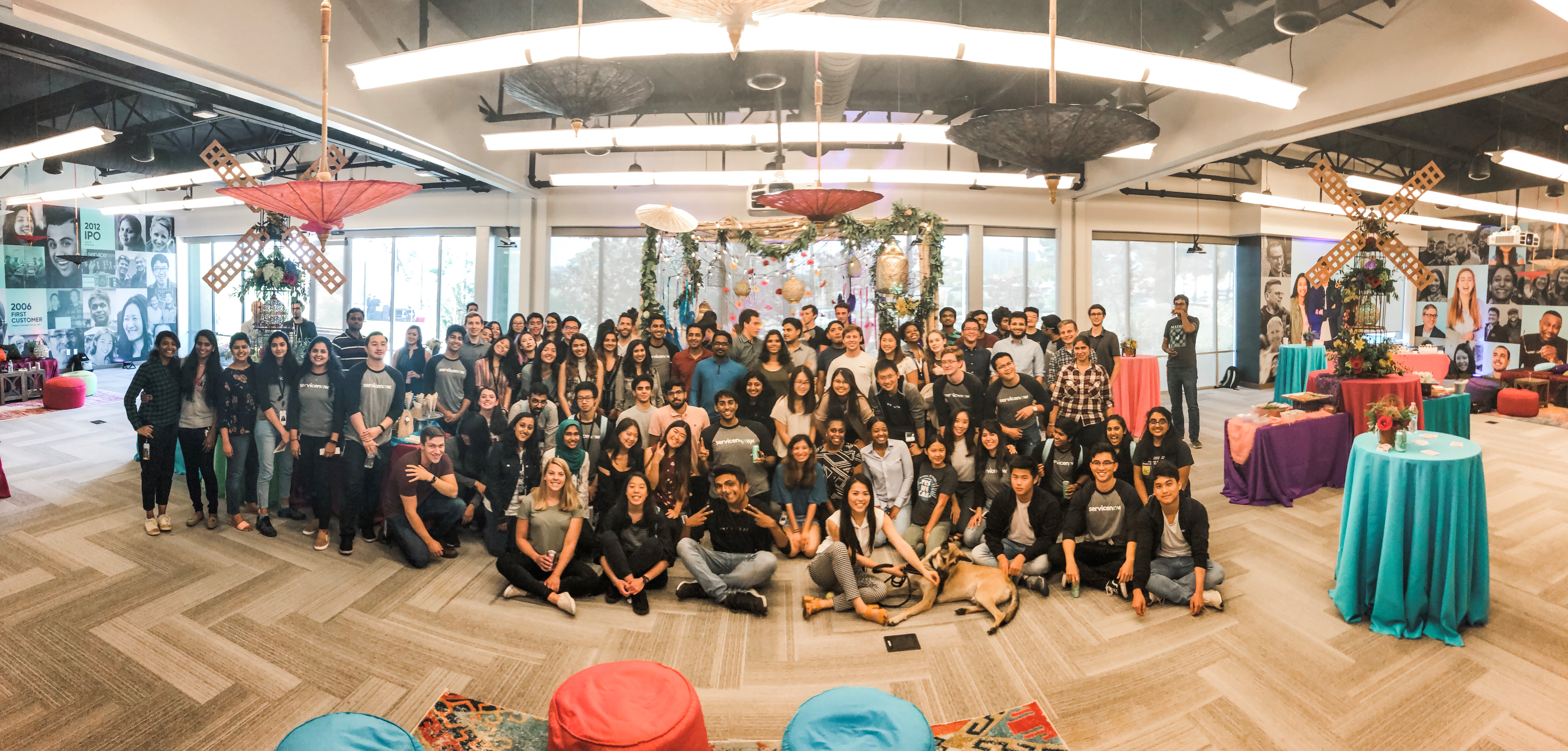 50-60 interns posing together for one large photo in a comfortable and decorated room.